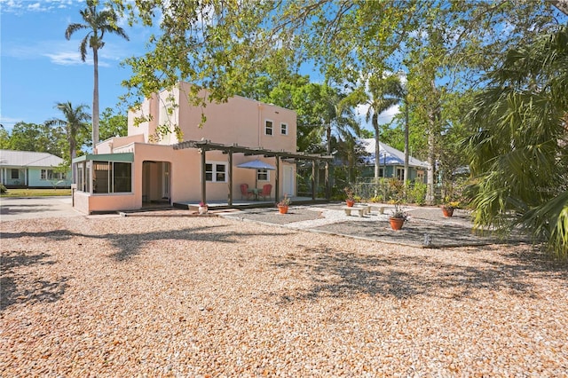 back of property with stucco siding, a pergola, a patio, and a sunroom