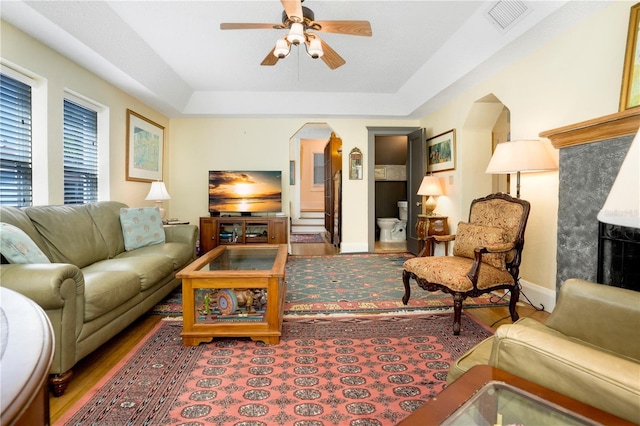 living area with wood finished floors, baseboards, visible vents, arched walkways, and ceiling fan