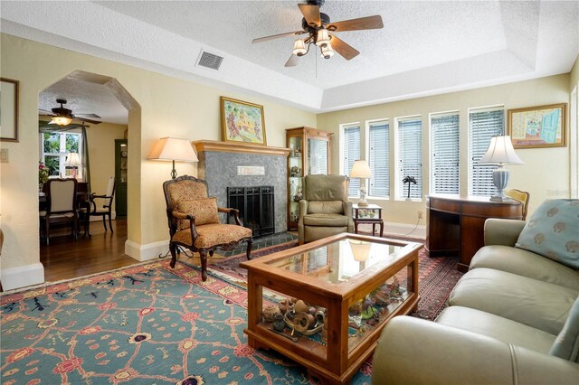living area featuring a tray ceiling, visible vents, and ceiling fan