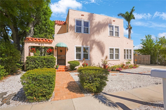 view of front of property with a gate, stucco siding, a tiled roof, and fence