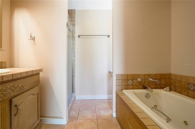 bathroom featuring tile patterned flooring, a shower stall, baseboards, a tub with jets, and vanity