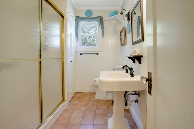 bathroom with baseboards, a stall shower, crown molding, tile patterned floors, and toilet
