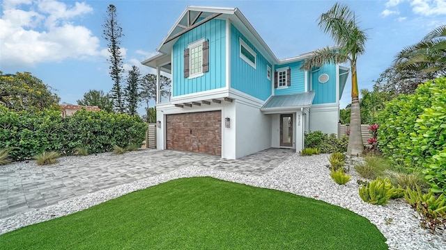 5930 Briarwood Ave, Sarasota, FL 34231 - view of front of property featuring an attached garage, decorative driveway, stucco siding, board and batten siding, and metal roof