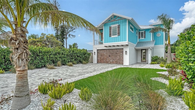 5930 Briarwood Ave, Sarasota, FL 34231 - view of front of home with metal roof, a garage, driveway, board and batten siding, and a standing seam roof