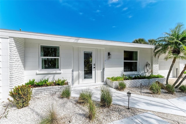 doorway to property featuring an attached garage and concrete block siding