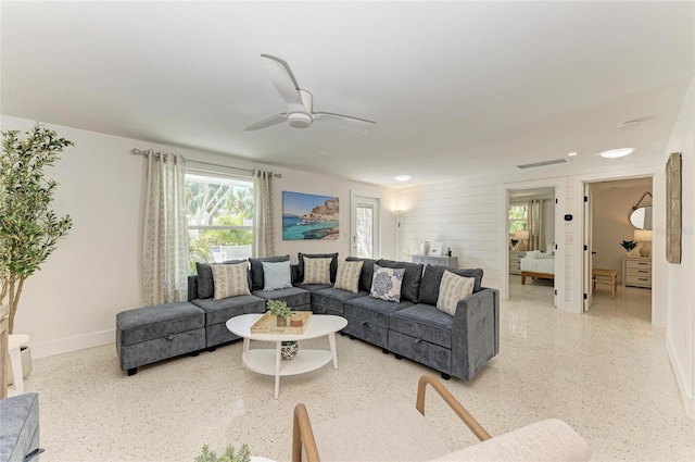 living room featuring baseboards, visible vents, light speckled floor, and ceiling fan