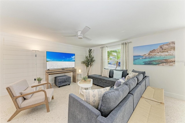 living area featuring baseboards, wood walls, and ceiling fan