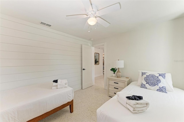 bedroom featuring visible vents, light speckled floor, and a ceiling fan