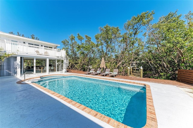 pool with stairway, a wooden deck, and a patio