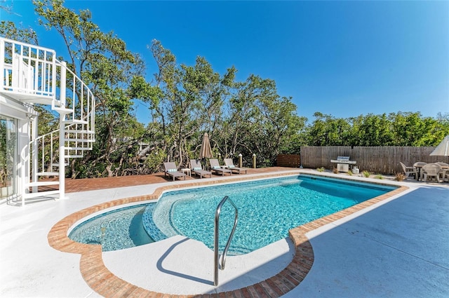 view of pool featuring a fenced in pool, fence, stairs, and a patio area