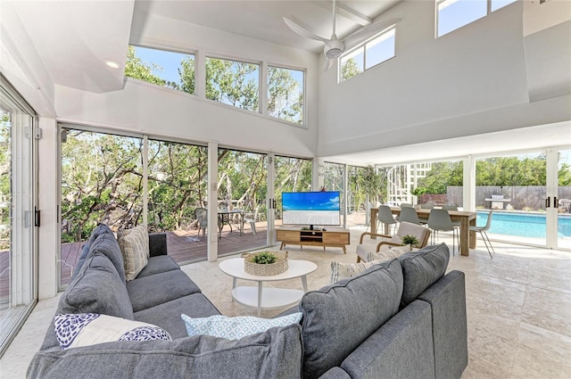 living area with a healthy amount of sunlight, a towering ceiling, and a ceiling fan