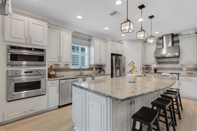 12711 Del Corso Loop, Bradenton, FL 34211 - kitchen with stainless steel appliances, wall chimney range hood, tasteful backsplash, light wood-style flooring, and recessed lighting