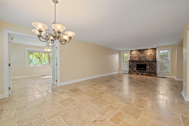 unfurnished living room featuring a fireplace, an inviting chandelier, baseboards, and stone tile flooring