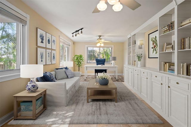 living area with baseboards and a ceiling fan