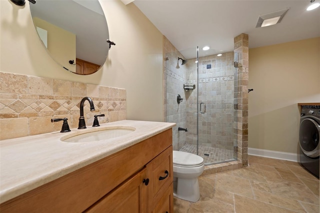 bathroom with stone finish floor, toilet, a shower stall, washer / dryer, and vanity