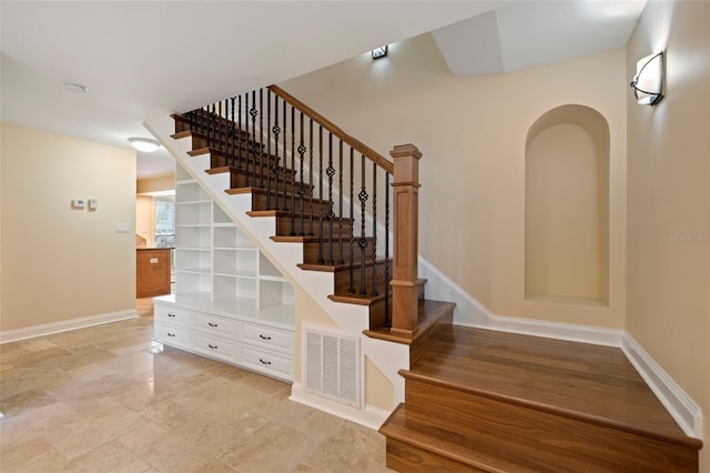 stairs featuring baseboards, visible vents, and stone finish floor