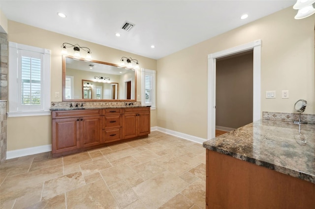 full bathroom with double vanity, baseboards, stone finish floor, and visible vents