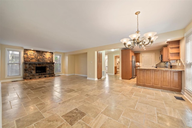 interior space featuring stone tile flooring, freestanding refrigerator, open shelves, visible vents, and open floor plan