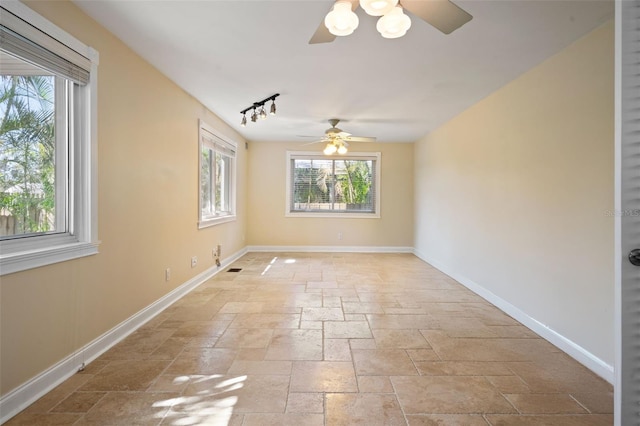 unfurnished room featuring plenty of natural light, a ceiling fan, and stone tile flooring