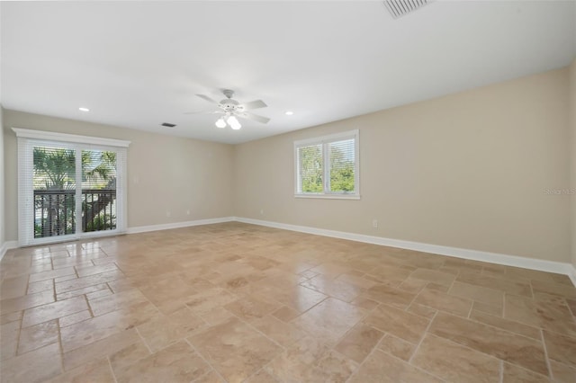 unfurnished room with ceiling fan, baseboards, a healthy amount of sunlight, and stone tile floors