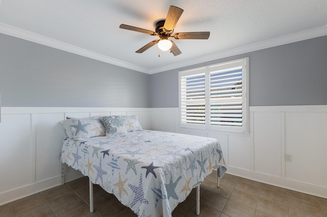 bedroom featuring a wainscoted wall, ornamental molding, and tile patterned flooring