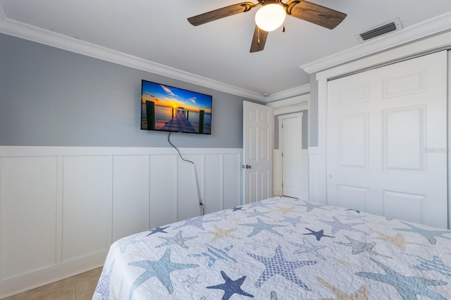 bedroom featuring wainscoting, tile patterned floors, crown molding, and visible vents