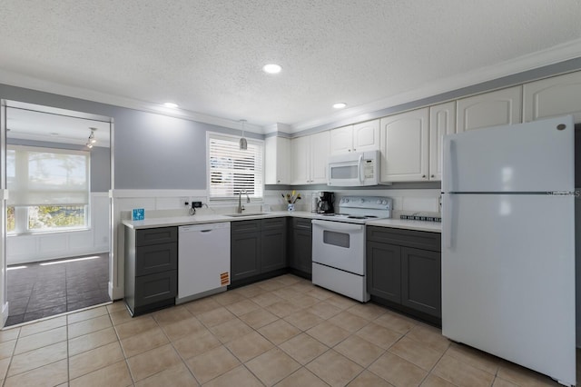 kitchen featuring light countertops, white appliances, a sink, gray cabinetry, and wainscoting
