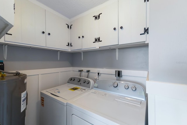 clothes washing area featuring water heater, a textured ceiling, wainscoting, independent washer and dryer, and cabinet space