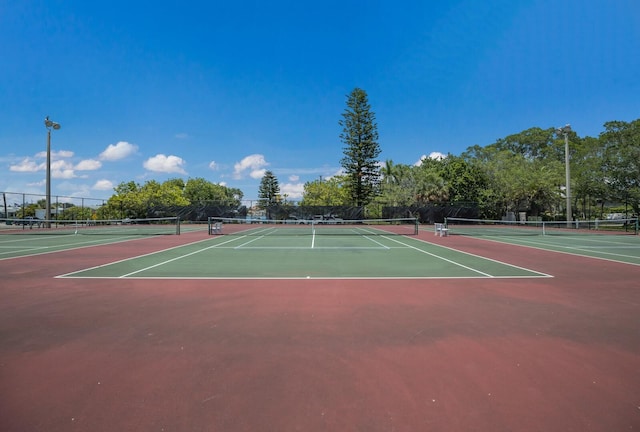 view of tennis court featuring community basketball court and fence