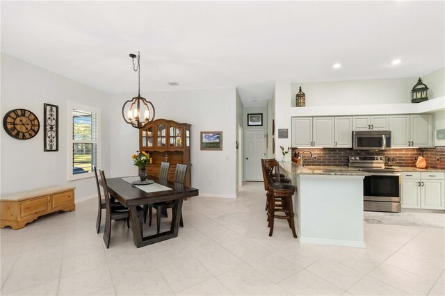 1118 Deardon Dr, Venice, FL 34292 - kitchen with a chandelier, a peninsula, stainless steel appliances, a breakfast bar area, and backsplash