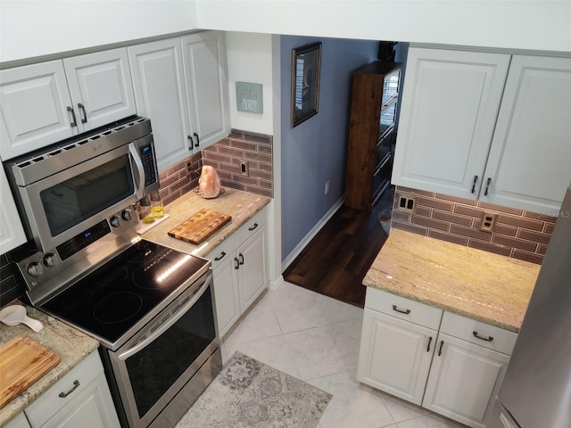 1118 Deardon Dr, Venice, FL 34292 - kitchen featuring tasteful backsplash, baseboards, white cabinets, light stone countertops, and appliances with stainless steel finishes