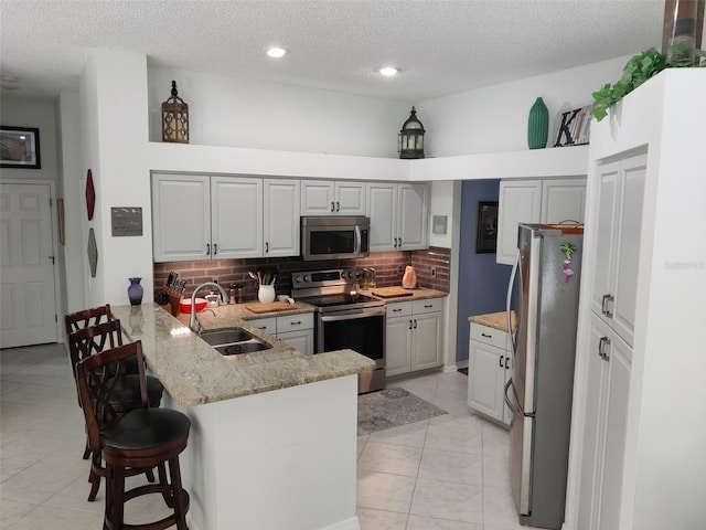 1118 Deardon Dr, Venice, FL 34292 - kitchen featuring a breakfast bar, backsplash, a sink, a peninsula, and appliances with stainless steel finishes