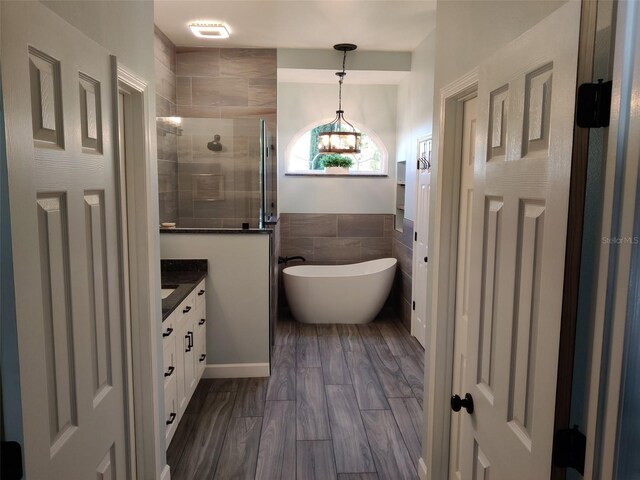 1118 Deardon Dr, Venice, FL 34292 - full bath featuring vanity, tile walls, a soaking tub, a stall shower, and wood finished floors