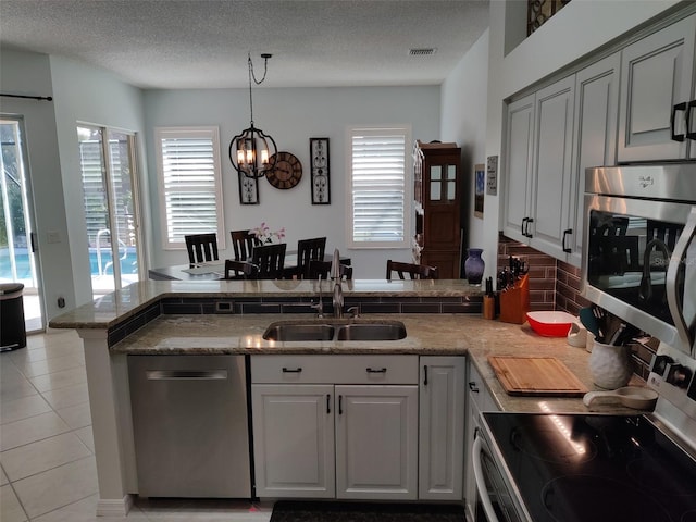 1118 Deardon Dr, Venice, FL 34292 - kitchen featuring a textured ceiling, appliances with stainless steel finishes, a sink, pendant lighting, and light tile patterned floors