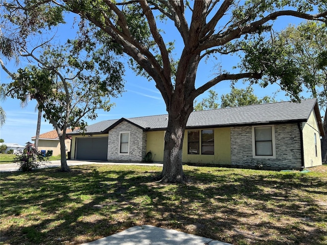 ranch-style home featuring a front yard, stone siding, a garage, and concrete driveway