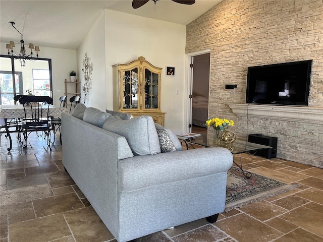 living area with high vaulted ceiling, stone tile flooring, and ceiling fan with notable chandelier