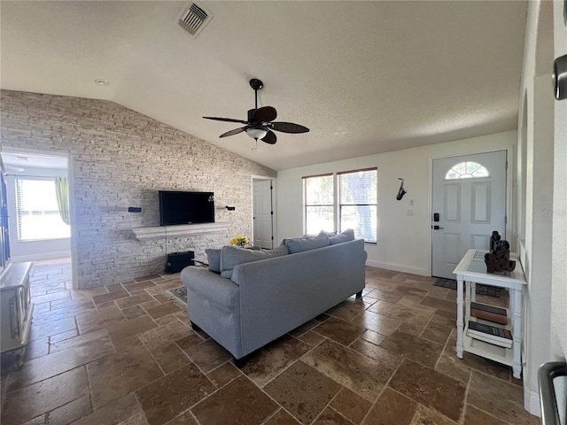 living area featuring stone tile flooring, a healthy amount of sunlight, and ceiling fan