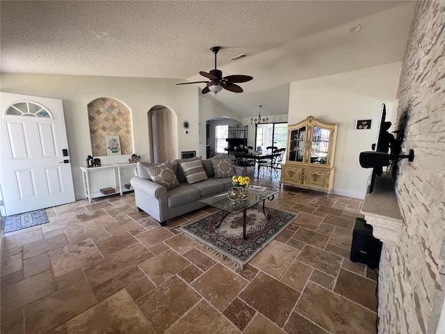 living room featuring visible vents, arched walkways, ceiling fan with notable chandelier, vaulted ceiling, and stone tile floors