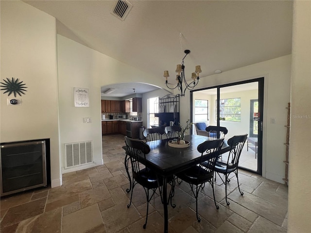 dining room featuring stone tile flooring, baseboards, visible vents, arched walkways, and an inviting chandelier