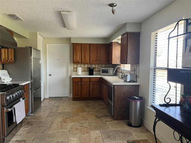 kitchen with light countertops, visible vents, stone tile flooring, white microwave, and gas range