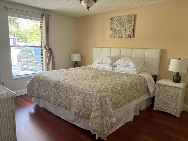 bedroom featuring baseboards, a textured ceiling, and wood finished floors