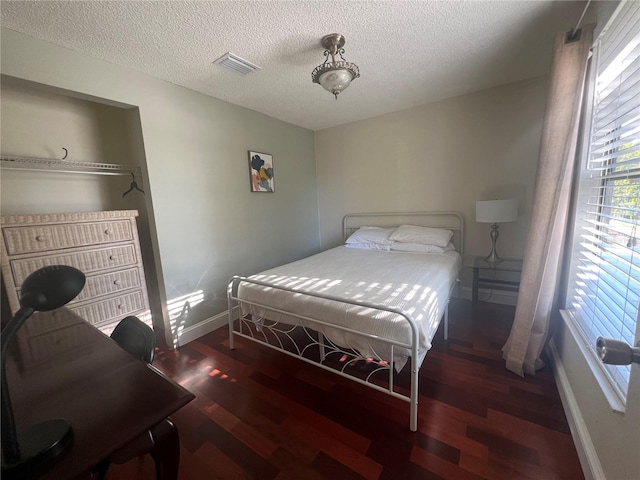 bedroom featuring baseboards, visible vents, wood finished floors, and a textured ceiling