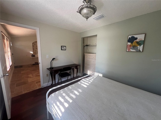 bedroom featuring baseboards, visible vents, a closet, and a textured ceiling