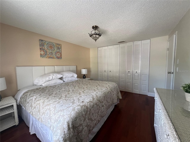 bedroom with dark wood-style flooring, a textured ceiling, a closet, and visible vents