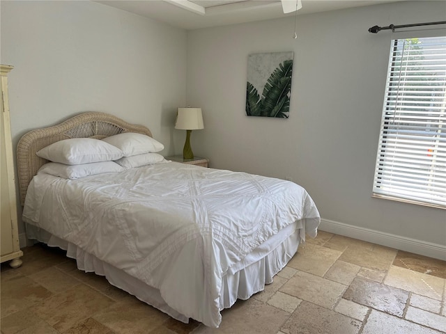 bedroom featuring stone tile floors and baseboards