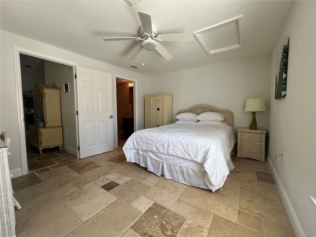bedroom with stone tile floors, attic access, baseboards, visible vents, and a ceiling fan
