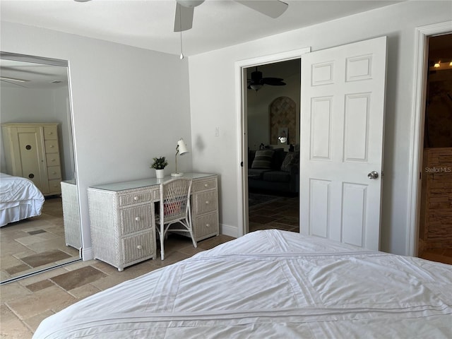 bedroom with baseboards, stone tile flooring, and a ceiling fan