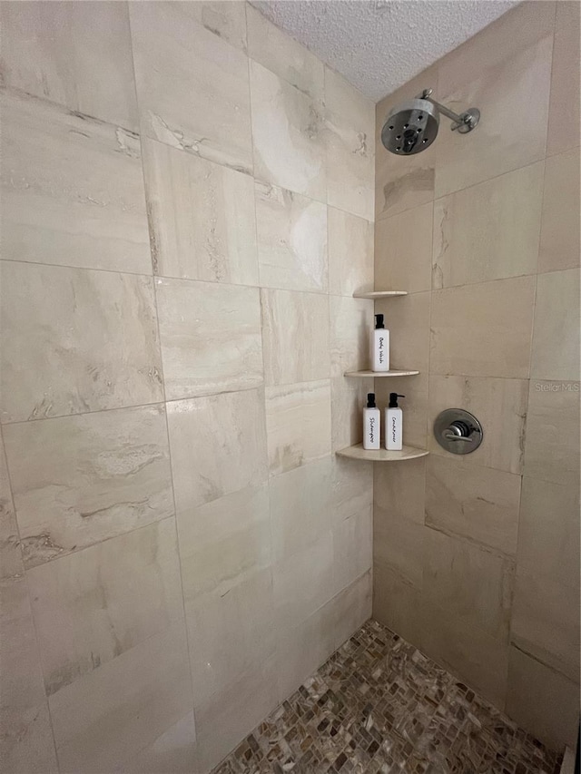 bathroom with a textured ceiling and a tile shower