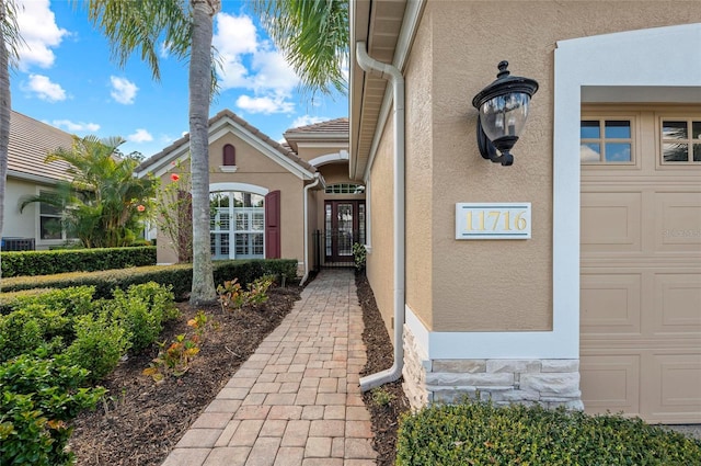 11716 Strandhill Ct, Lakewood Ranch, FL 34202 - doorway to property with a gate, stone siding, stucco siding, a tiled roof, and a garage