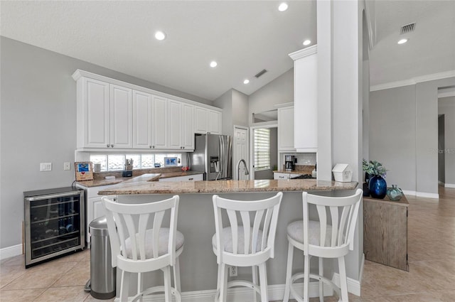 11716 Strandhill Ct, Lakewood Ranch, FL 34202 - kitchen with white cabinetry, light tile patterned floors, stainless steel fridge with ice dispenser, wine cooler, and light stone countertops